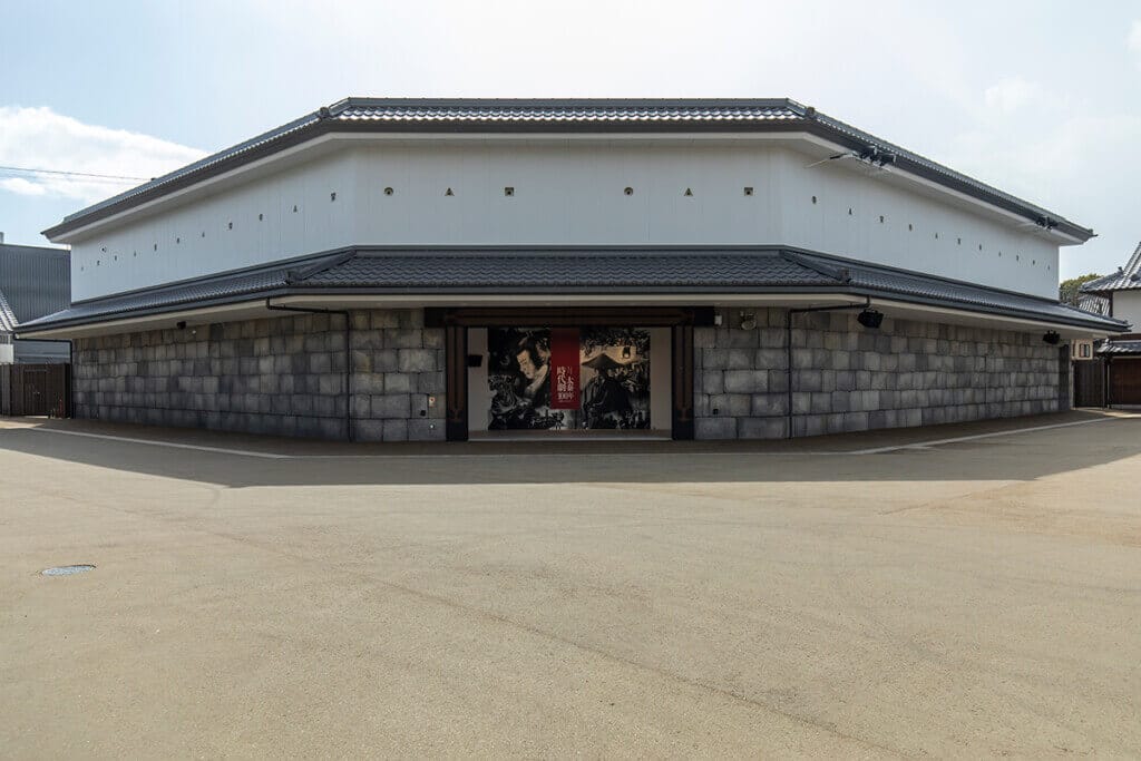 Large traditional-style building with a white upper level and stone base, entrance showing black-and-white posters.