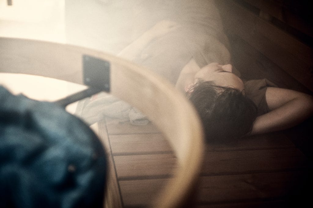 Blurred top-down view of a person lying on a wooden floor with an arm raised over the head.