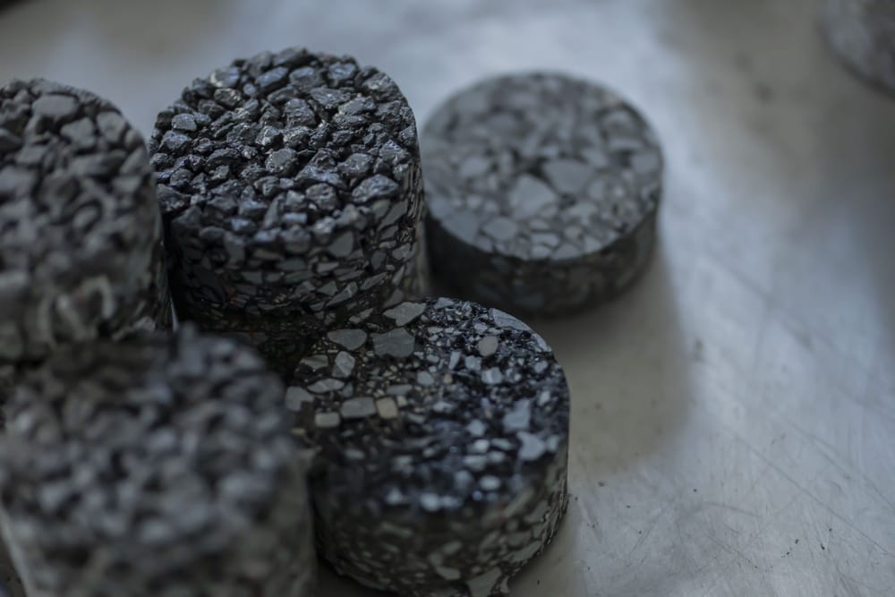 Round charcoal briquettes with a speckled, terrazzo-like surface on a metal tray/surface