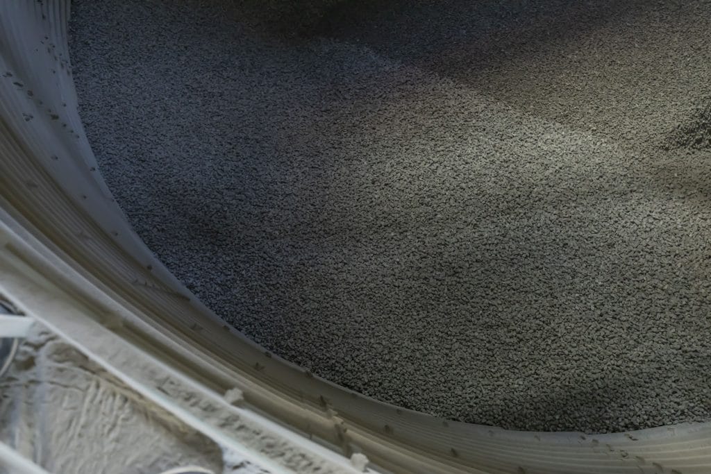 Close-up of a light-colored curved metal frame along a gravel-covered floor.